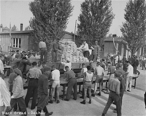 Američané vykládají černý chléb po osvobození koncentračního tábora v Dachau